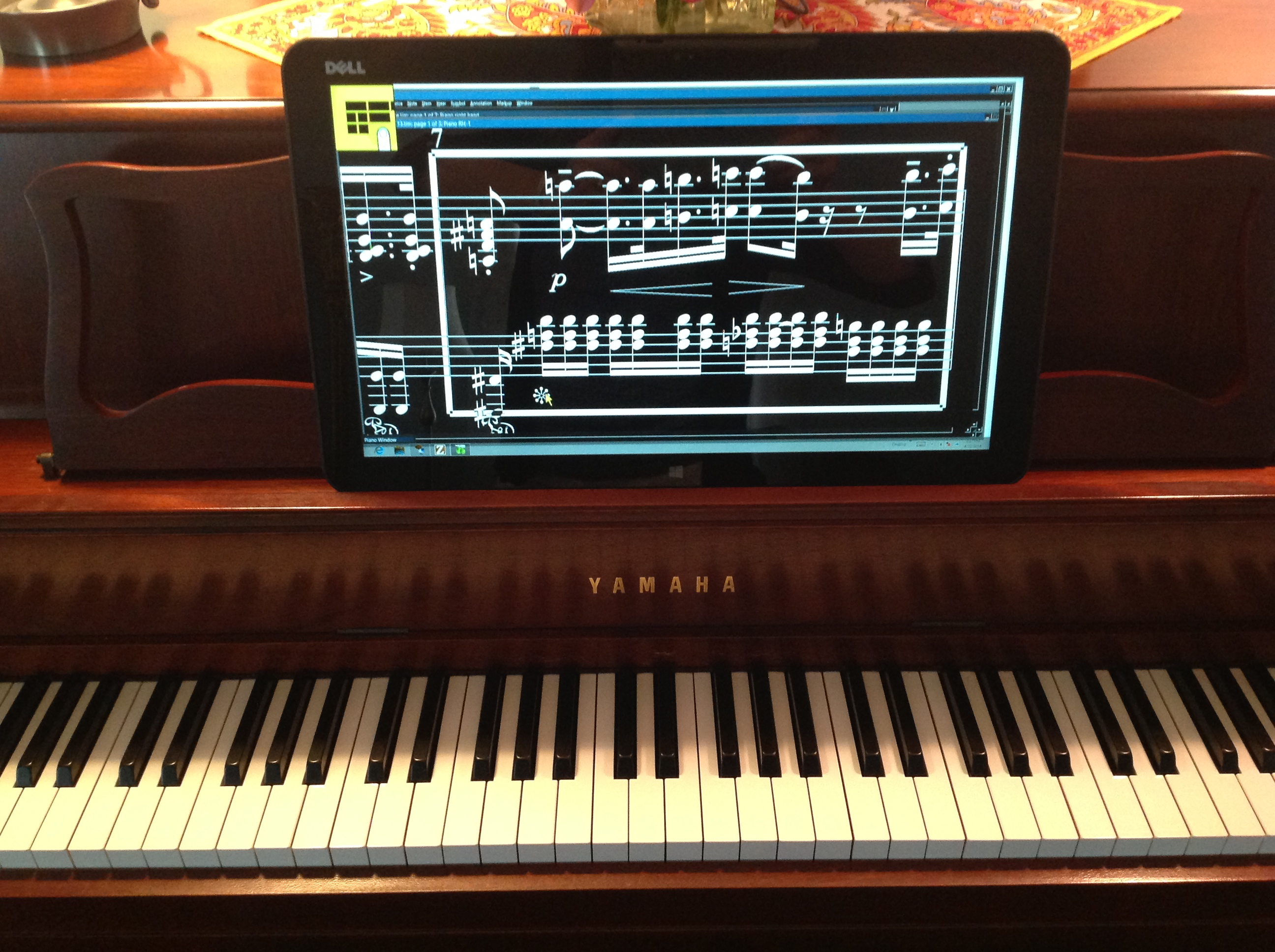 Image of Lime Lighter Leggiero model mounted on the music rack of a piano and displaying magnified music as white notes on a black background on a grand staff